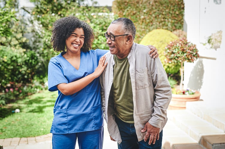Elderly man with his nurse, smiling in a garden